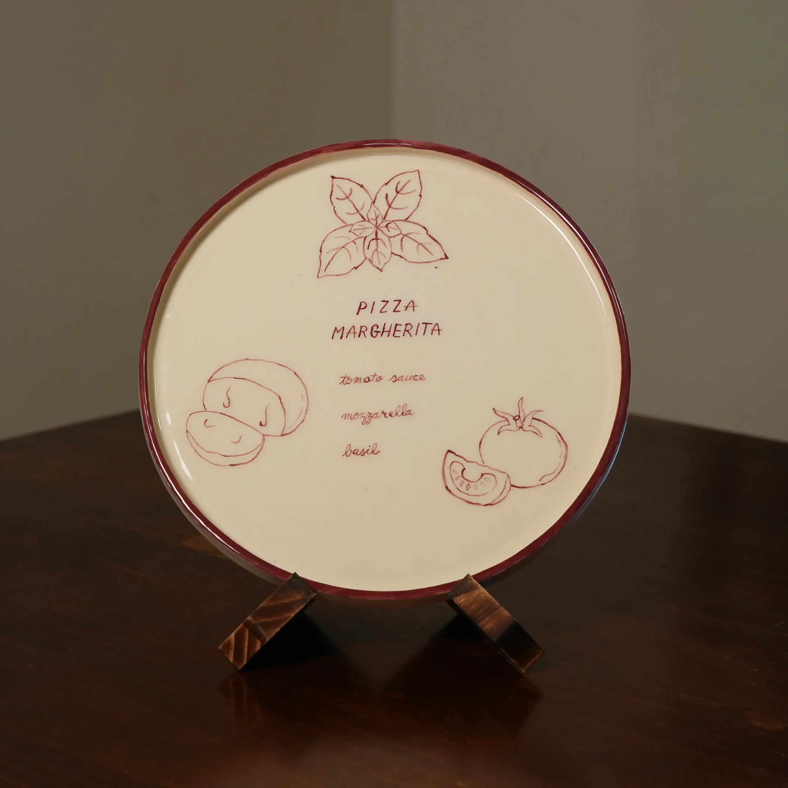 Hand-painted Margherita pizza plate displayed on its stand, by Franci Pots