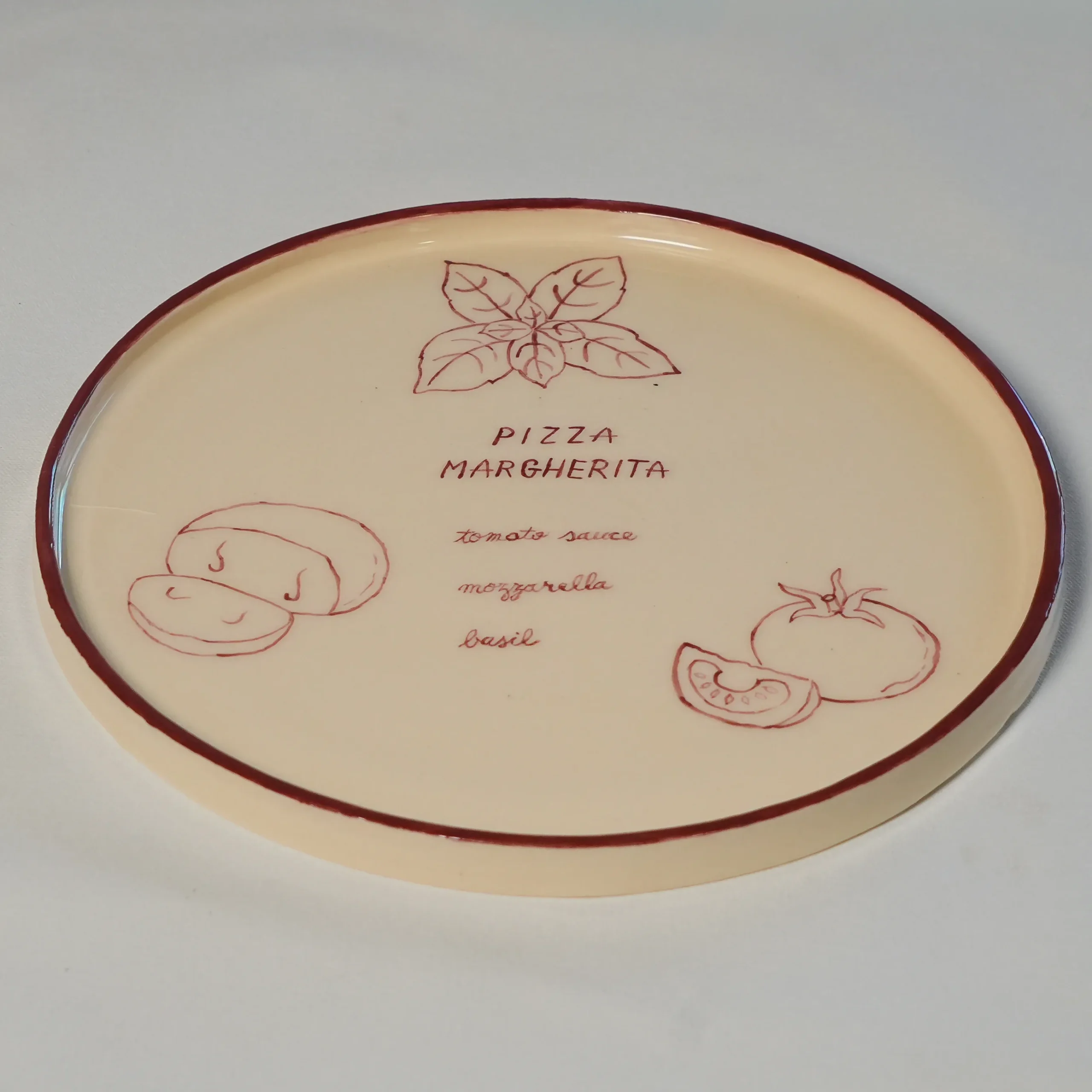 Three-quarter view of a hand-painted Margherita pizza plate by Franci Pots