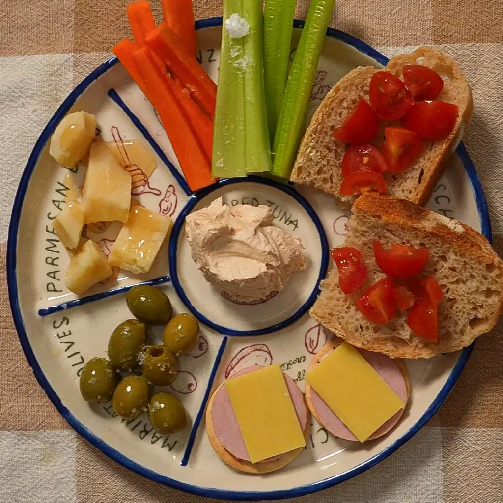 Ceramic grazing platter filled with food, its hand-painted mini recipes showing around the rim
